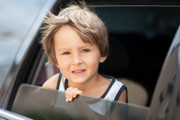 Little cute child, boy, looking out the window of a car - Foto, imagen