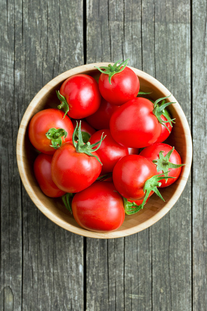 red tomatoes in wooden bowl - Foto, afbeelding