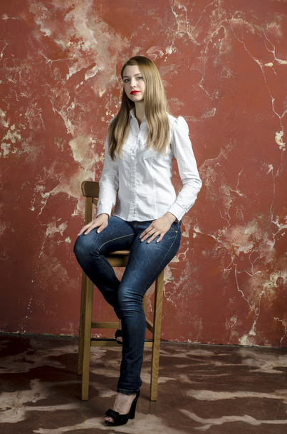 Young slim beautiful young blond woman with long legs and hair in shirt and jeans - Φωτογραφία, εικόνα