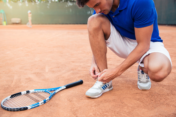 Male tennis player tying shoelaces  - 写真・画像