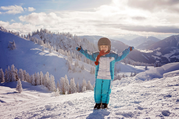 Adorable little boy with blue jacket and a helmet, skiing  - Фото, зображення