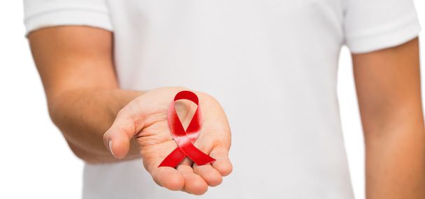 hand with red aids or hiv awareness ribbon - Foto, afbeelding