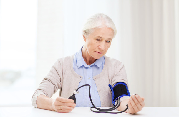 old woman with tonometer checking blood pressure - Φωτογραφία, εικόνα