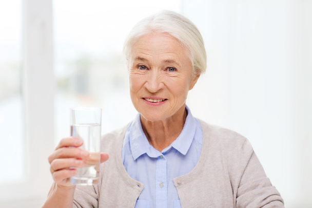 happy senior woman with glass of water at home - Foto, Imagem