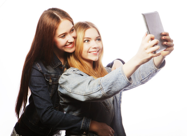 Two pretty young women taking a self portrait with a tablet - Zdjęcie, obraz