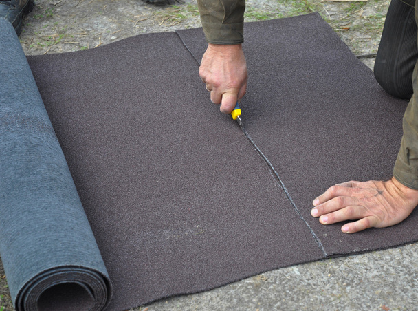 Dakdekker snijden roll dakleer of bitumen tijdens vochtdicht maken - Foto, afbeelding