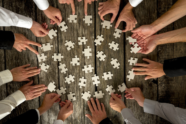 Hommes d'affaires mains tenant des pièces de puzzle sur la table
 - Photo, image