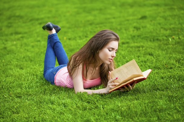 Young beautiful brunette girl reading a book outdoor - Fotó, kép