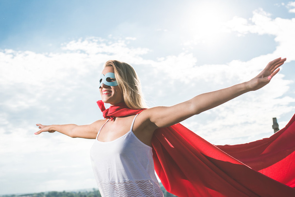 Блондинка супергерой стоит над голубым небом и выброшенные руки
 - Фото, изображение