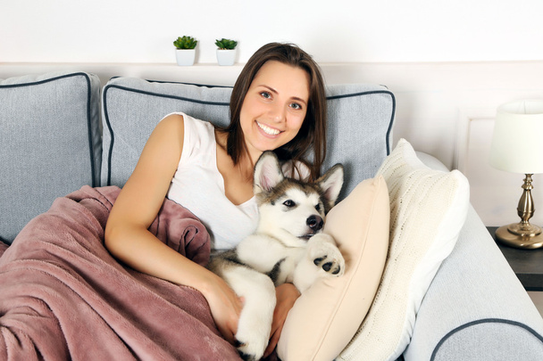Young woman lying with malamute dog - Foto, afbeelding
