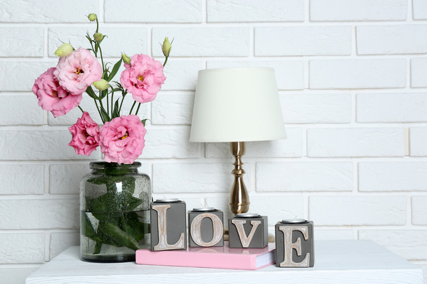 Beautiful flowers with table lamp on brick wall background - Фото, зображення