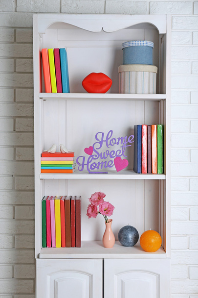 Books and decor on shelves in cupboard - Fotó, kép