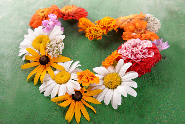 Fresh colorful flowers in shape of heart wooden table, closeup - Fotoğraf, Görsel