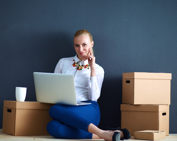 Woman sitting on the floor near a boxes  with laptop  - Φωτογραφία, εικόνα