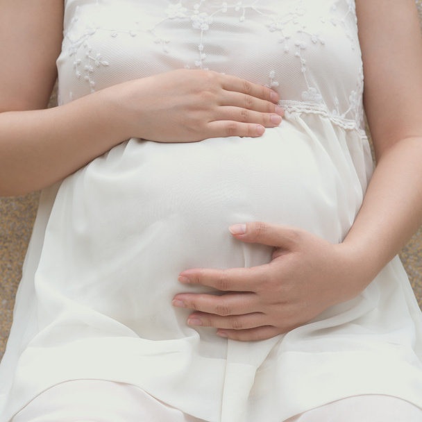 jeune femme enceinte mettant la main sur le ventre sentant son bébé, composition carrée
 - Photo, image