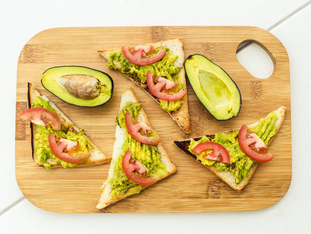 Vegan sandwich with avocado and tomatoes on cutting board - Fotoğraf, Görsel