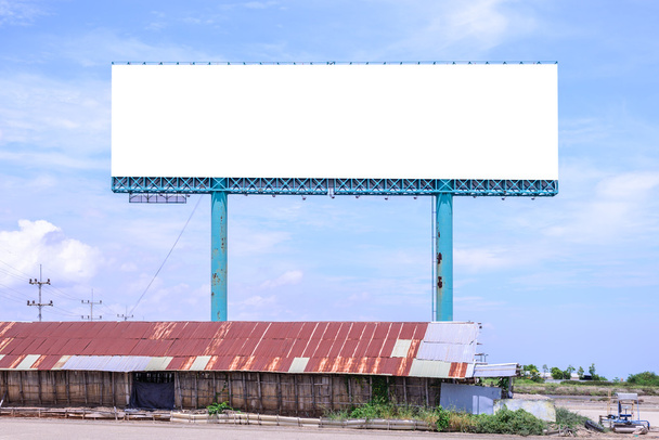 Cartelera en blanco detrás del techo oxidado del cobertizo de la sal con el cielo azul para la publicidad
. - Foto, imagen