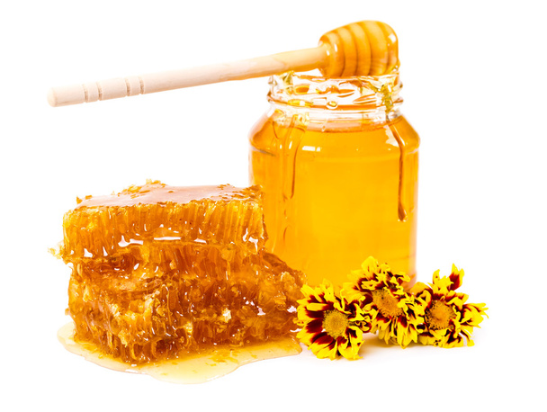 Sweet honeycomb and jar of honey with stick and flowers  - Photo, Image