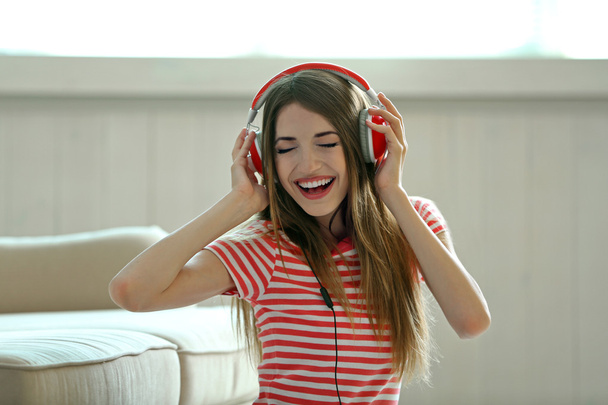 Woman listening music in headphones in room - Foto, immagini