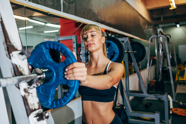 athletic girl sets weight on barbell in the gym - Photo, Image