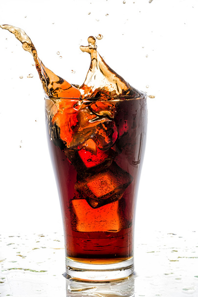 Ice cube droped in cola glass and cola splashing - Fotoğraf, Görsel
