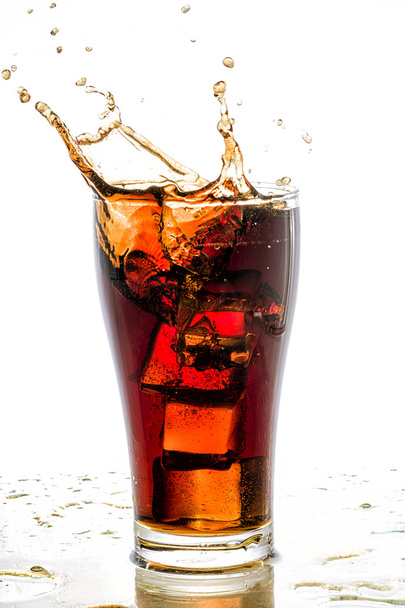Ice cube droped in cola glass and cola splashing - Foto, afbeelding