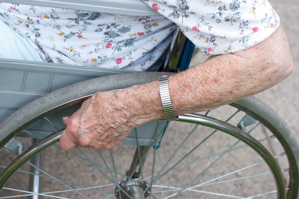 Senior's hand on wheel of wheelchair - Φωτογραφία, εικόνα