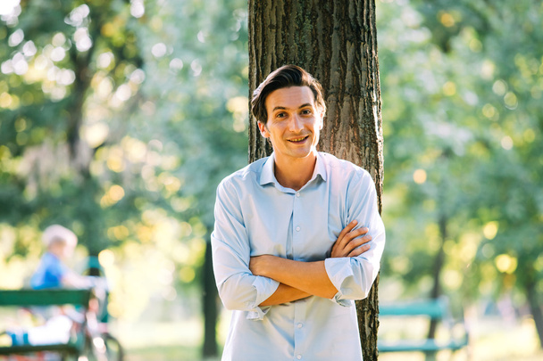 handsome adult man leaning on a tree - Photo, Image