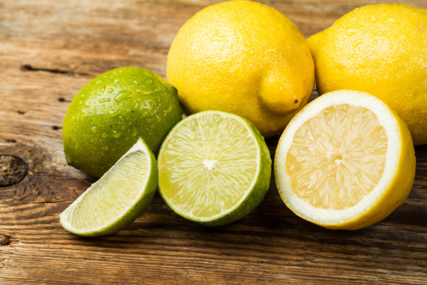Limões e limão frescos e suculentos em uma superfície de madeira
 - Foto, Imagem