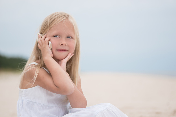 Beautiful young girl talking on the phone at the seaside - Zdjęcie, obraz