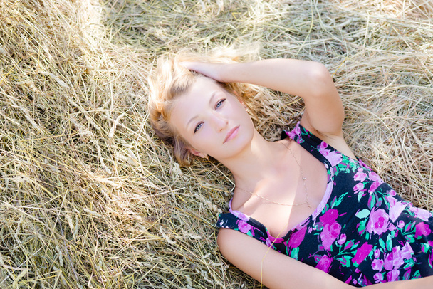 Blond girl is lying on haystack - Zdjęcie, obraz