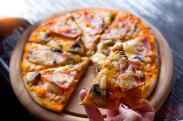 fresh pizza on a wooden plate in female hands. Selective focus. - Photo, Image