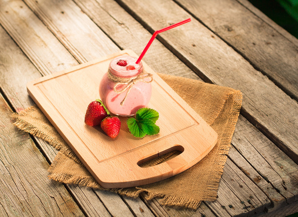 Strawberry smoothie in glass jar, over wood table. - 写真・画像