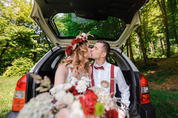 Happy bride and groom sitting in the trunk of a car  - Photo, Image