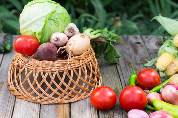 Harvest time. A basket of vegetables on a wooden table - Φωτογραφία, εικόνα
