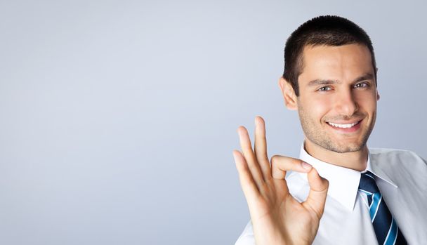 Businessman with okay gesture, against grey - Фото, зображення