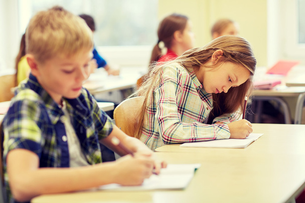 group of school kids writing test in classroom - Фото, изображение