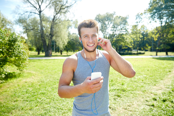 happy man with earphones and smartphone at park - Foto, afbeelding