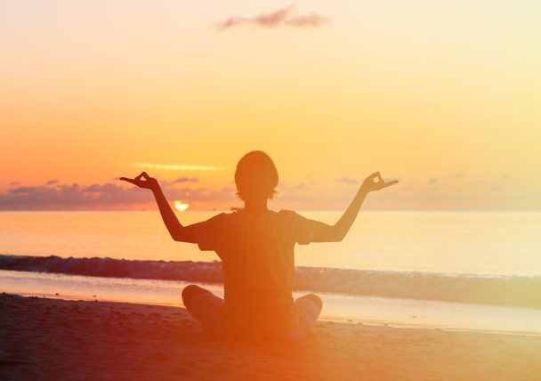 Sylwetka młodego człowieka robi joga na zachodzie słońca - Zdjęcie, obraz