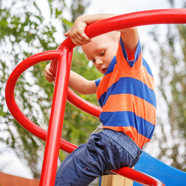 Ładny mały chłopiec bawi się na placu zabaw w lecie - Zdjęcie, obraz