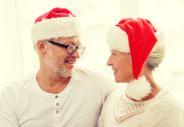 happy senior couple in santa helper hats at home - Фото, изображение
