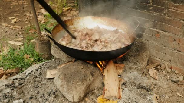 Размешивание свинины во фритюре внутри вока деревянной палкой над открытым огнем
 - Кадры, видео