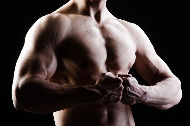 Homem muscular posando em estúdio escuro - Foto, Imagem