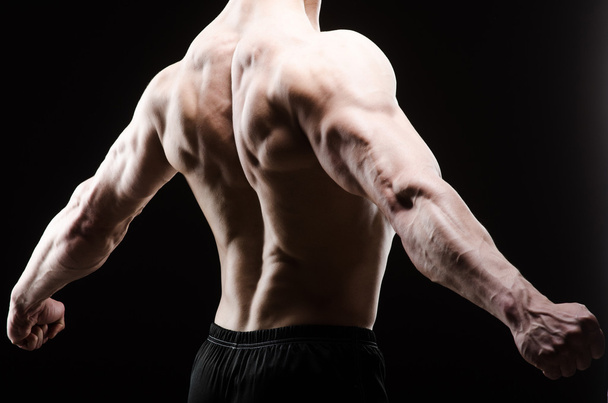 Homem muscular posando em estúdio escuro - Foto, Imagem