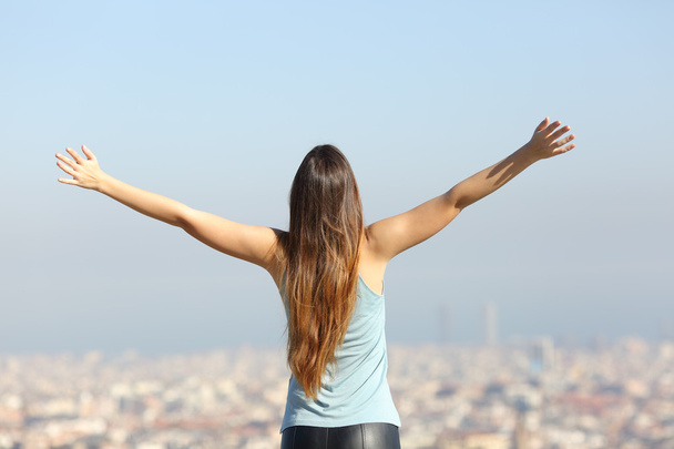 Mulher turística feliz levantando braços olhando para a cidade
 - Foto, Imagem