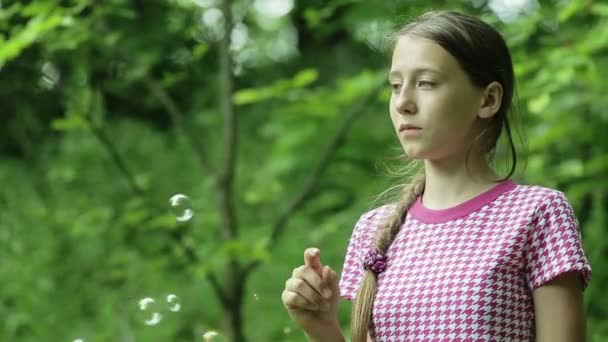 Mladá dívka úlovky mýdlové bubliny v parku - Záběry, video
