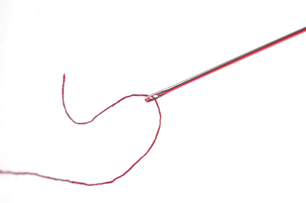 Nadel und Faden mit roten Reflexen - Foto, Bild