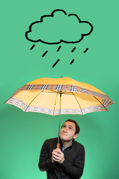 Junger Mann mit Regenschirm blickt auf eine Regenwolke - Foto, Bild