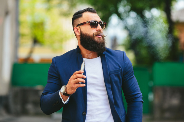 hombre con barba fuma cigarrillo electrónico
 - Foto, imagen