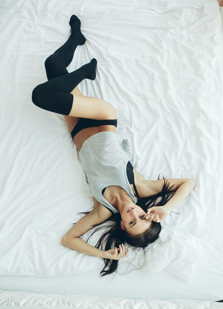 красивая молодая девушка позирует на белой кровати
 - Фото, изображение
